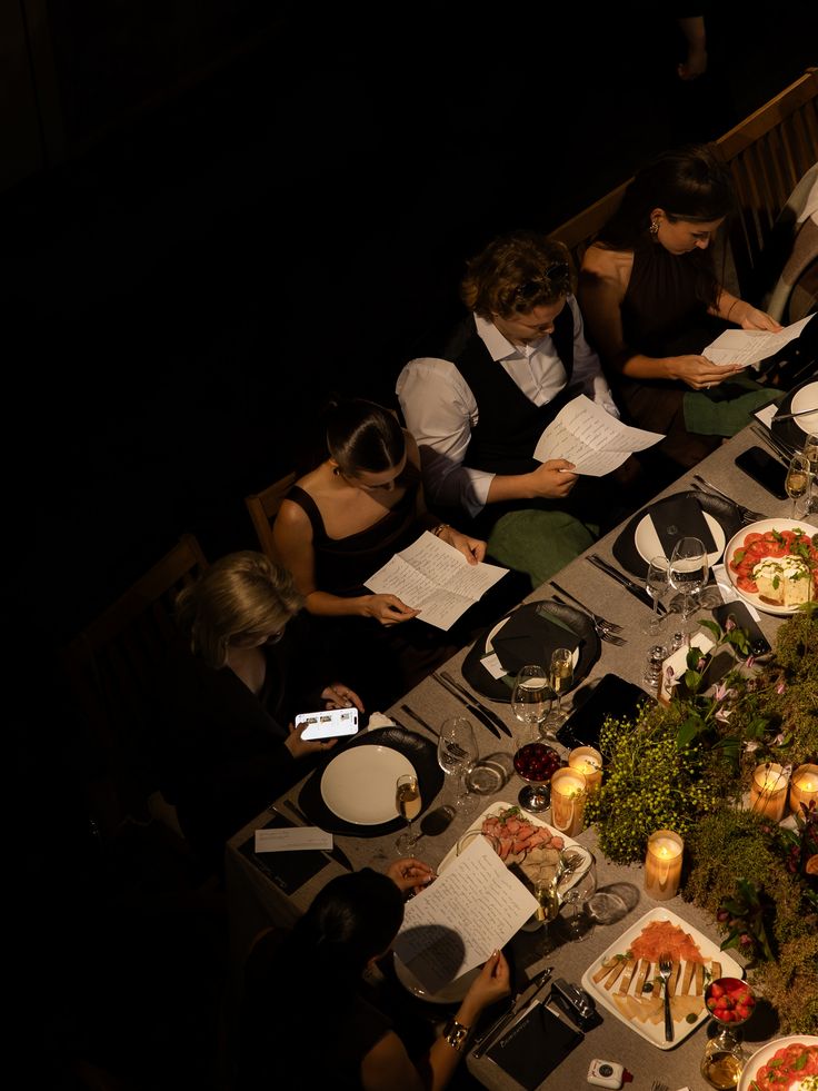 A candlelit table of guests reading their scripts