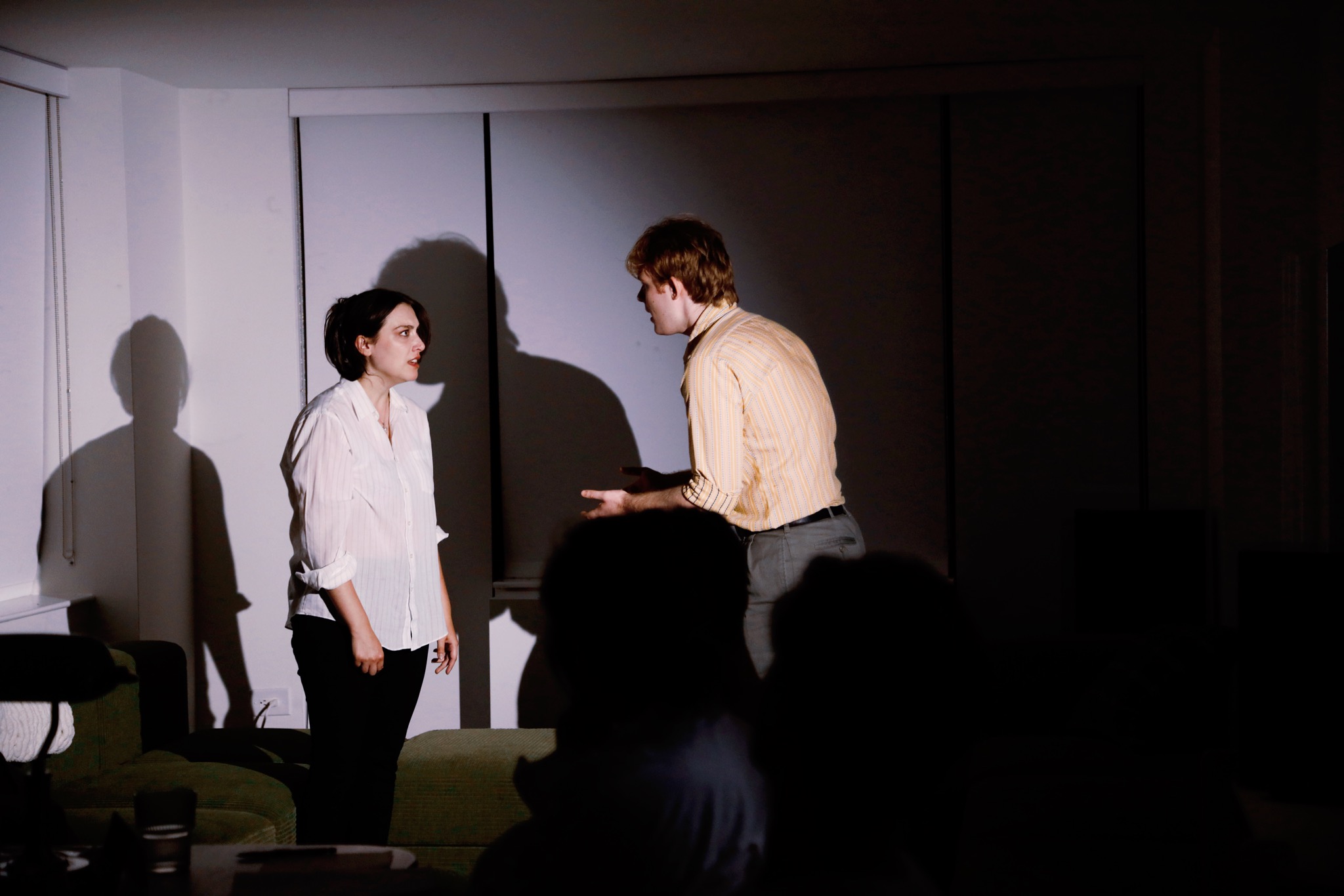 Two characters in a heated exchange before a watching audience